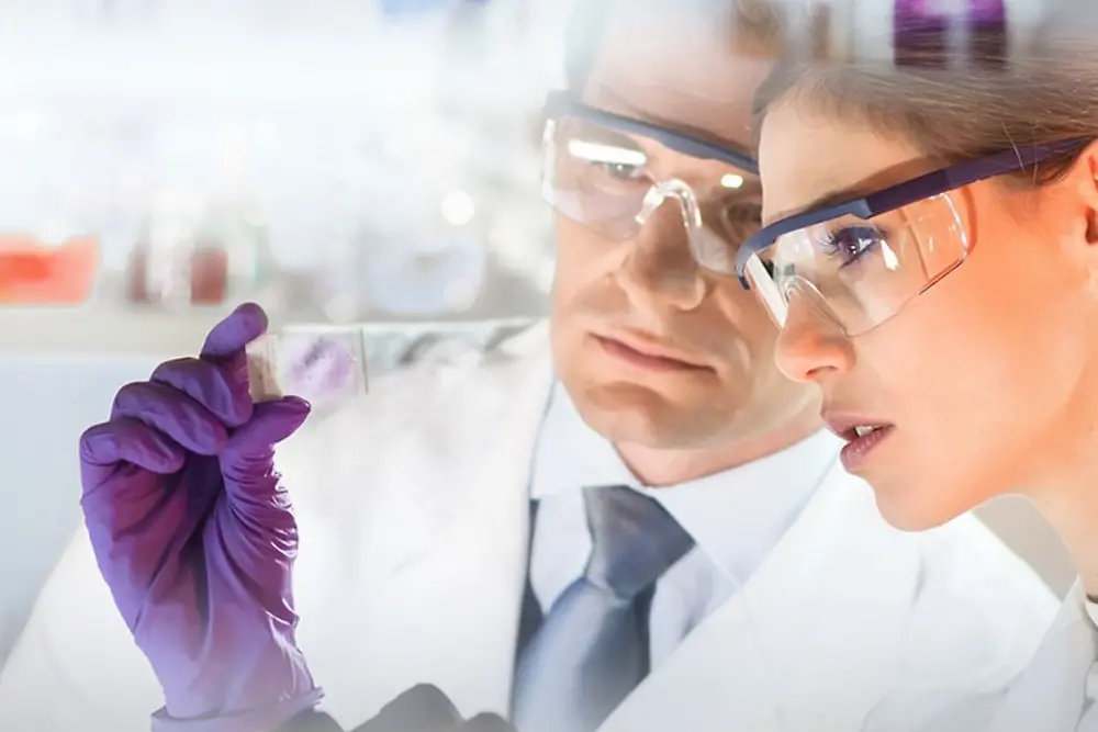 Faces of a woman and man looking at a sample being in a laboratory 