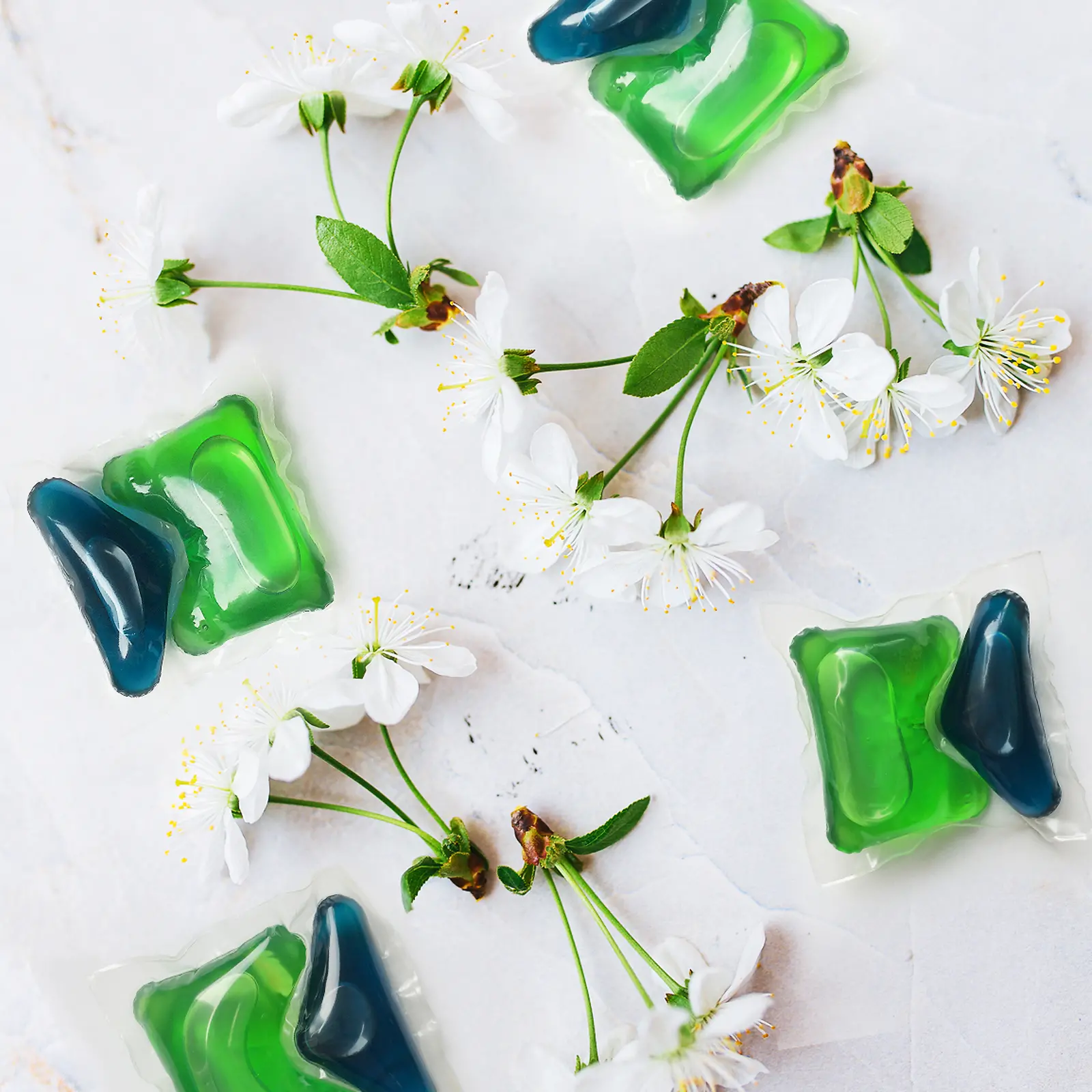 Etrafında kiraz çiçekleri olan iki adet yeşil ve mavi Henkel Persil tableti