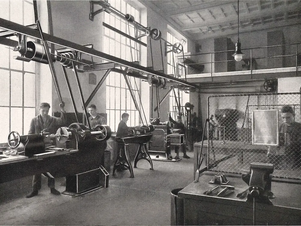 Metal işleme atölyesinde makineler üzerinde çalışan çıraklar.